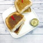 grilled turkey reuben sandwich on white plate with white wood background