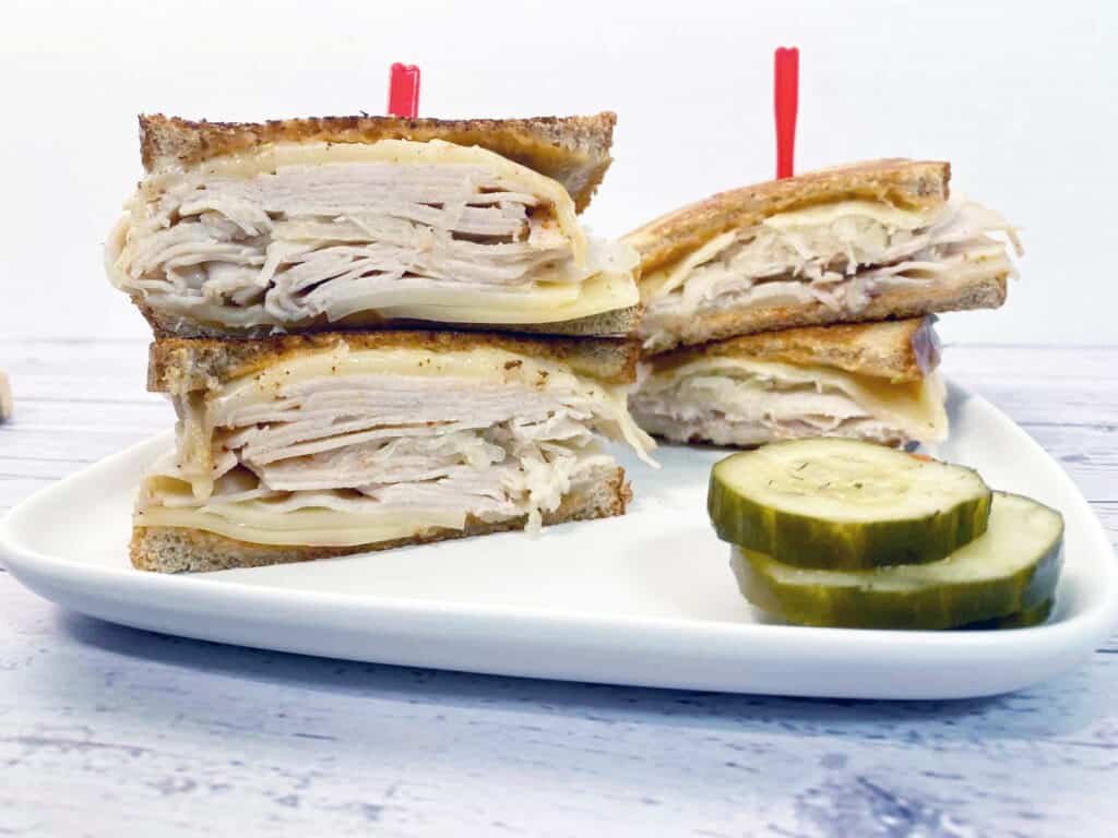 front facing image of turkey reuben sandwich with layers of turkey, swiss cheese and sauerkraut between toasted rye bread