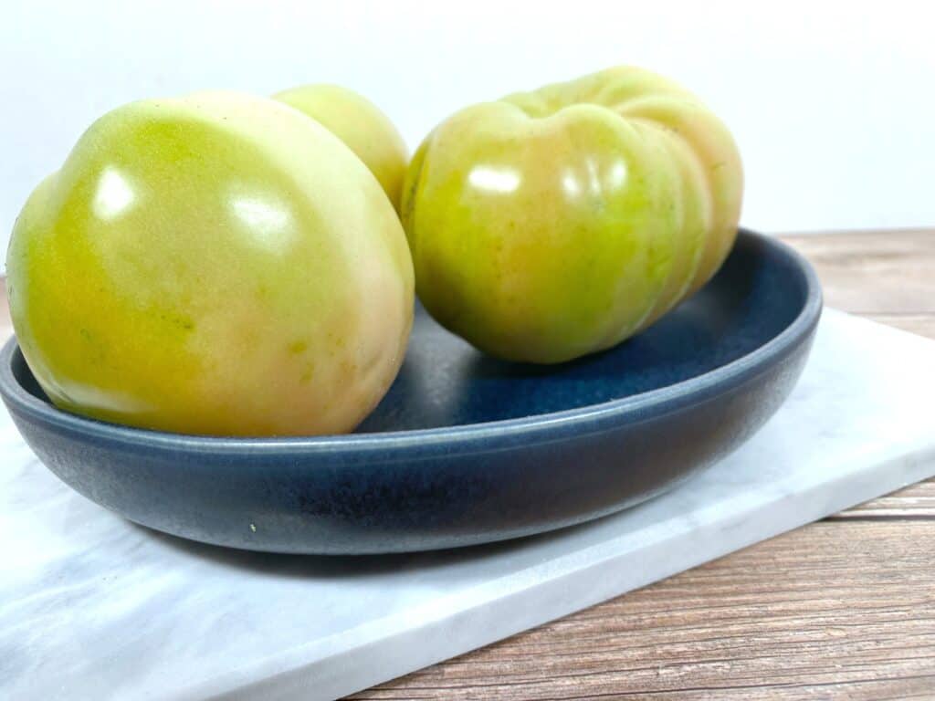 green tomatoes in a dark blue bowl