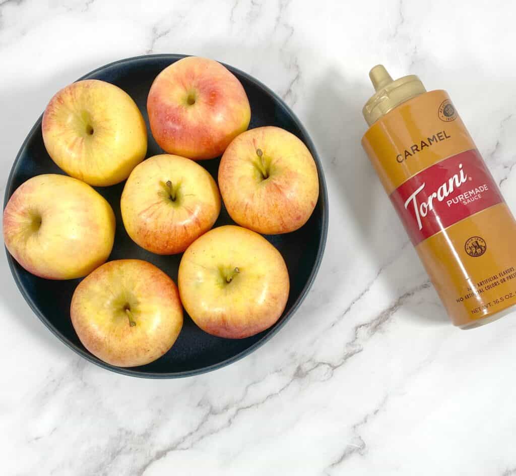 red apples in a blue bowl, caramel sauce next to it 