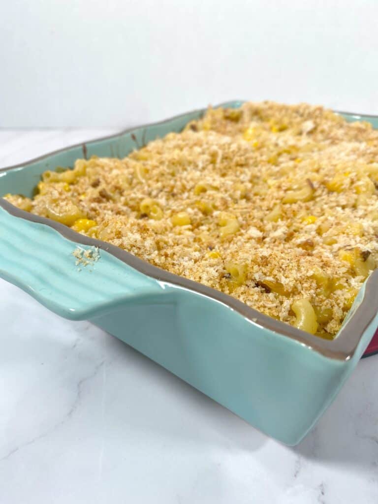 side angle picture of corn macaroni and cheese casserole in a teal dish