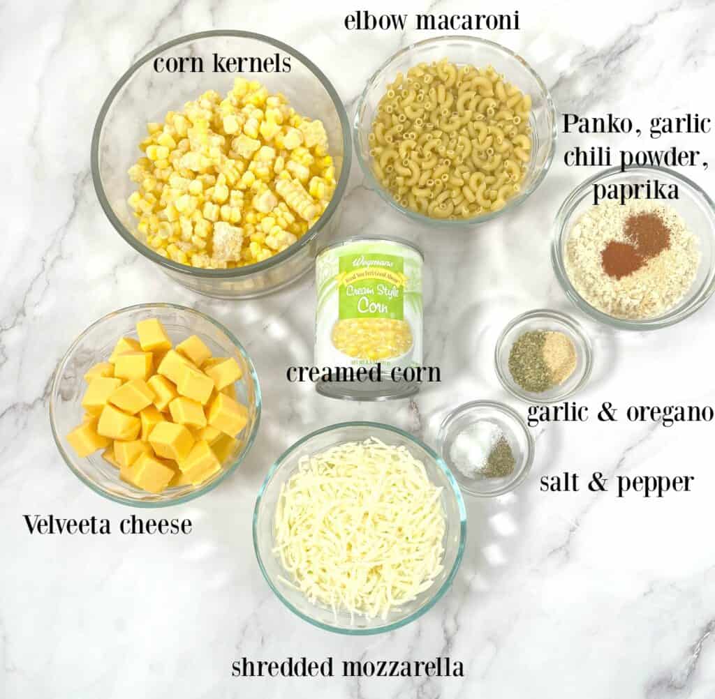 ingredients laid out on marble background to make corn macaroni and cheese casserole 