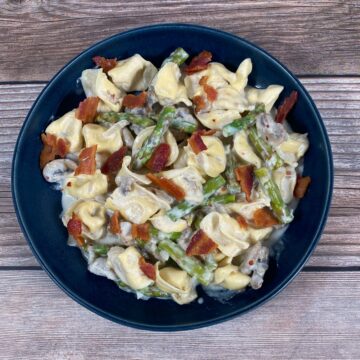 mushroom and asparagus tortellini with parmesan cheese in a blue bowl