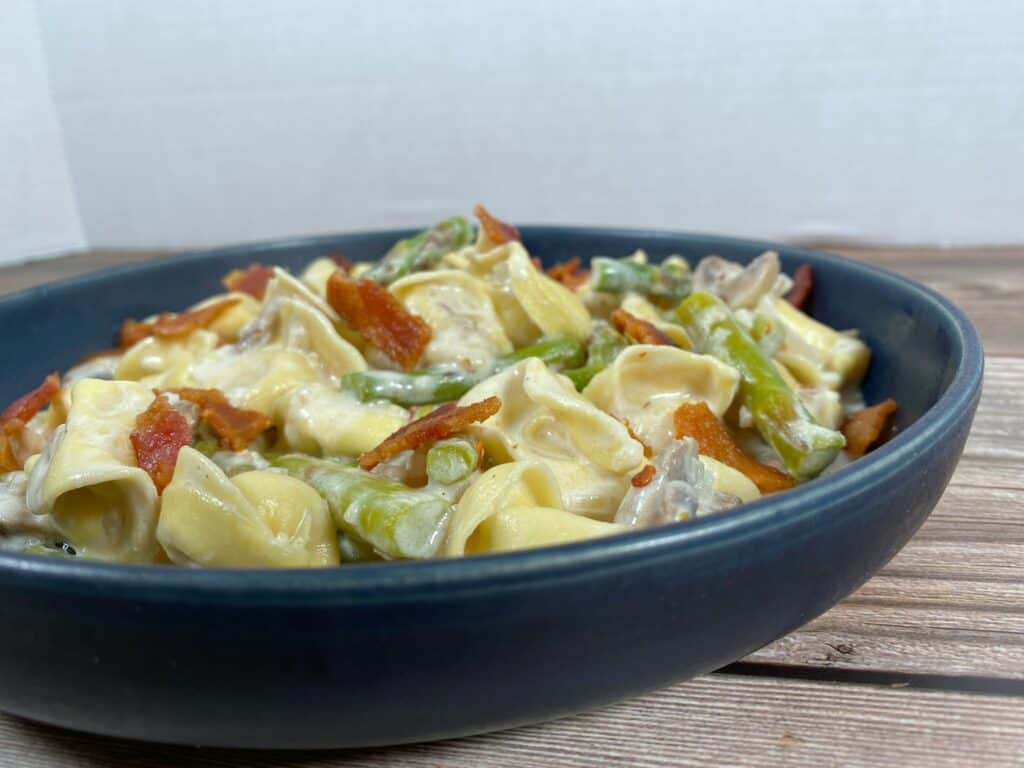 asparagus and mushroom tortellini in a blue bowl