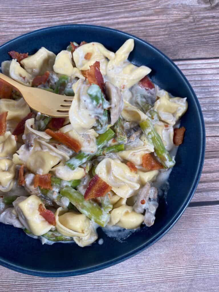 asparagus and mushroom tortellini in a blue bowl