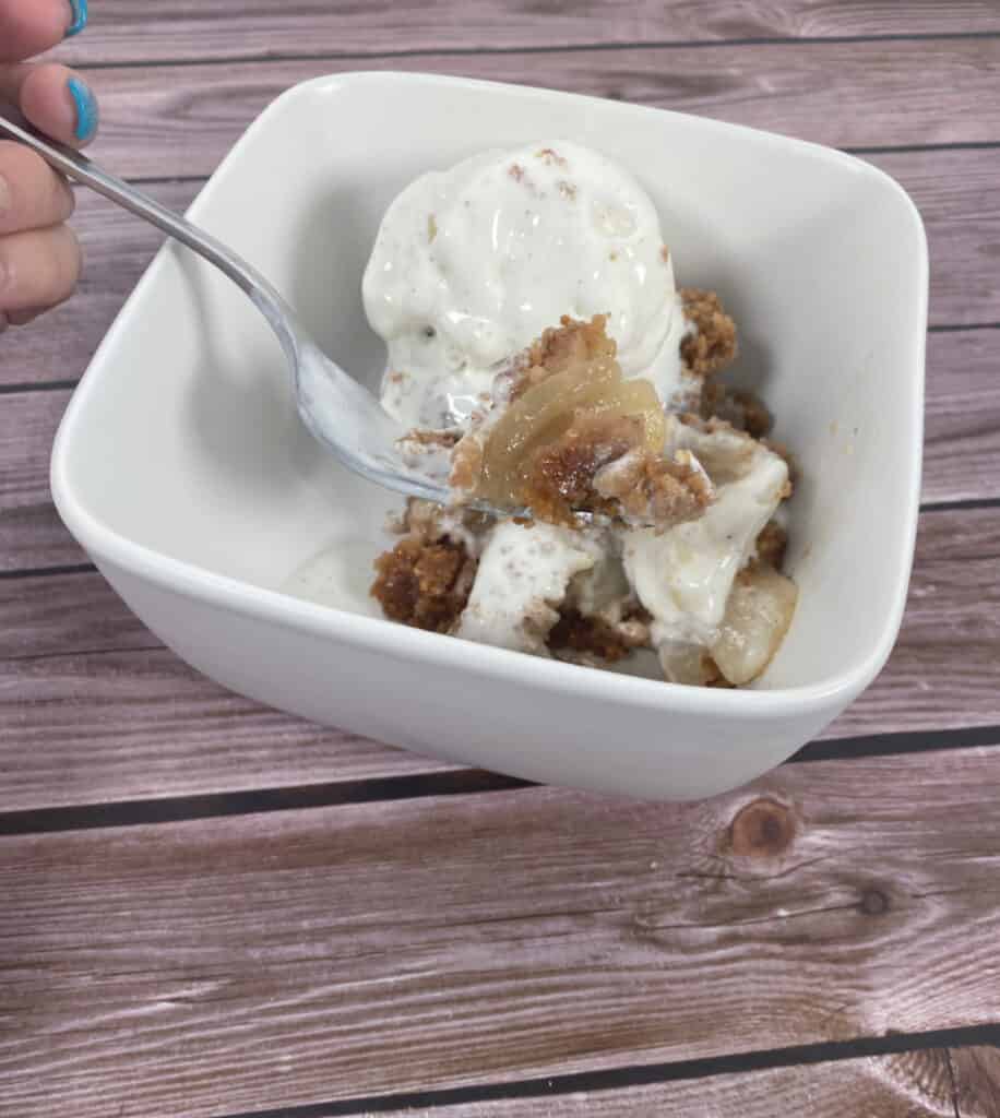 pear brown betty in a bowl with vanilla ice cream