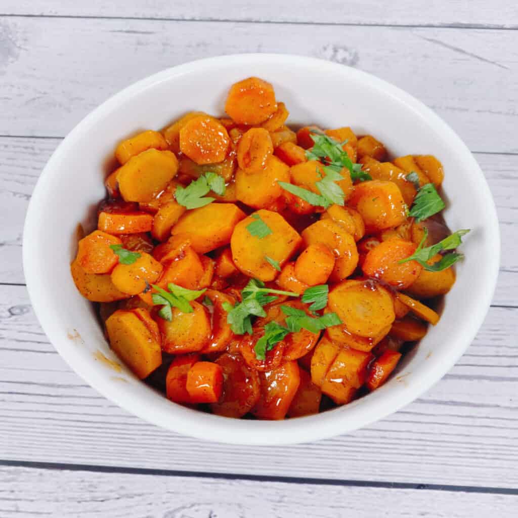 cardamom brown sugar carrots topped with fresh parsley in a white bowl