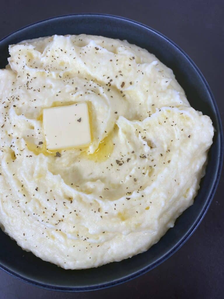a bowl of creamy, homemade mashed potatoes with a pat of butter melting on top
