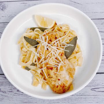 chicken cutlet on a bed of fettuccine pasta with fried sage leaves and a squeeze of lemon