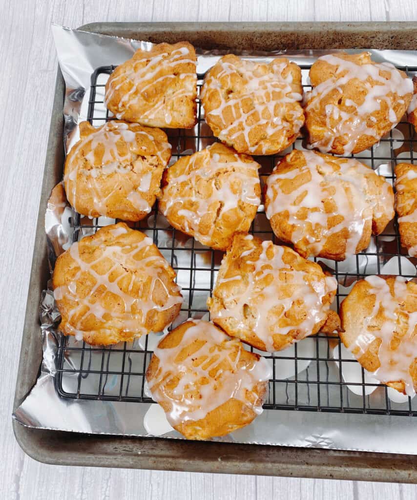 Air fried apple fritters drizzled with glaze sit on a cooling rack