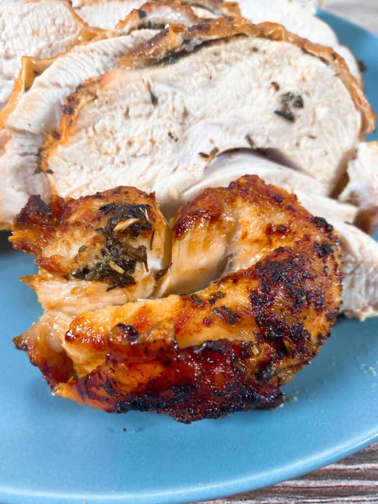 slices of seasoned turkey cooked in an air fryer sit on a blue plate