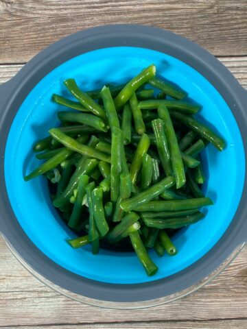 freshly blanched green beans sit in a colander