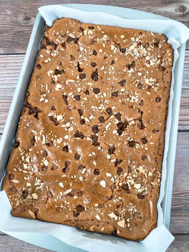 9x13 baking dish of almond orange brownies, topped with chocolate chips and slivered almonds.