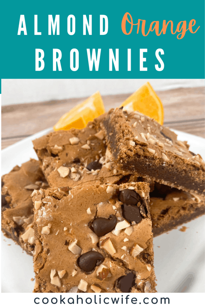 A white plate has a high stack of Almond Orange Brownies. Behind the brownies sits orange segments. 