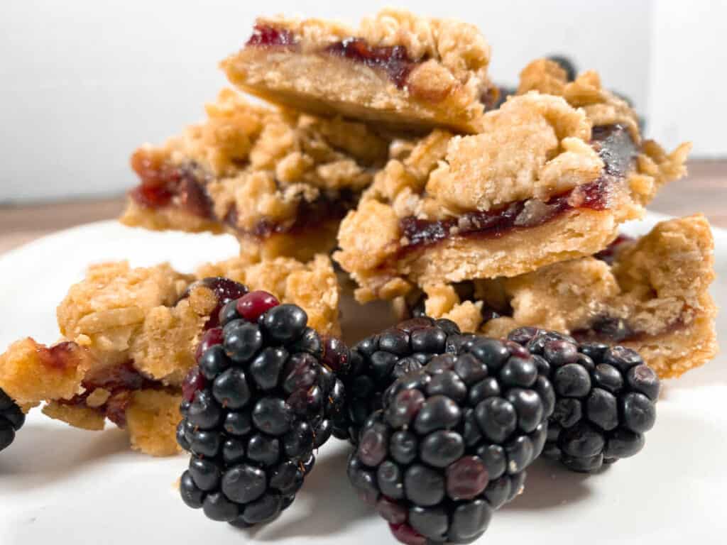 stack of blackberry oat crumble bars with fresh blackberries in front 