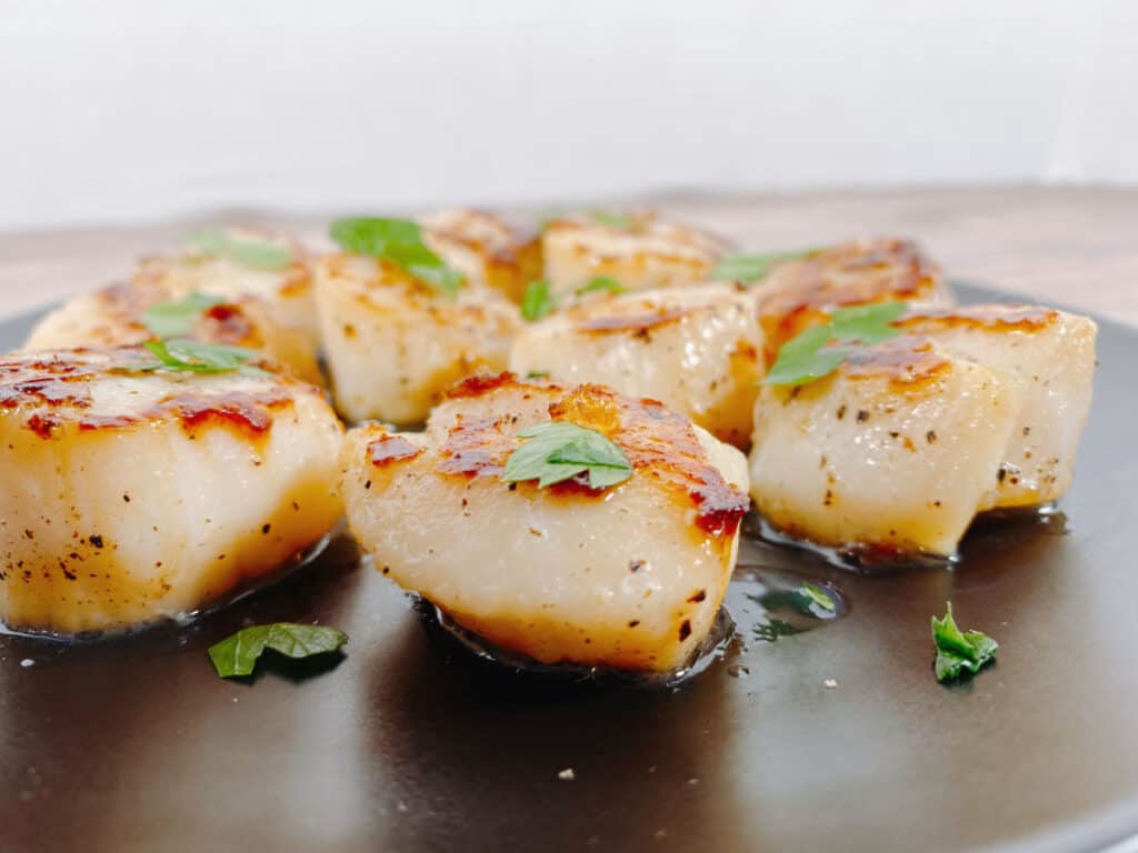 side view of scallops on a black plate 