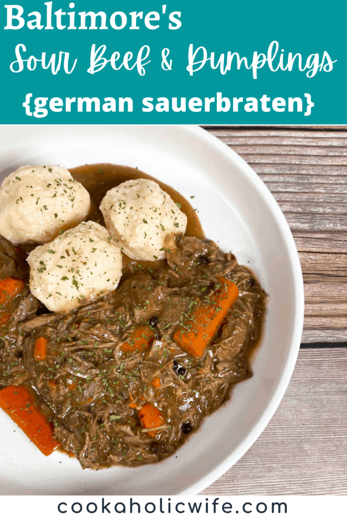 A shallow white dish sits on a wooden background. At the top left of the dish sits homemade potato dumplings sprinkled with fresh parsley and under that is the sour beef and carrots, shredded beef, in a pot roast style. 