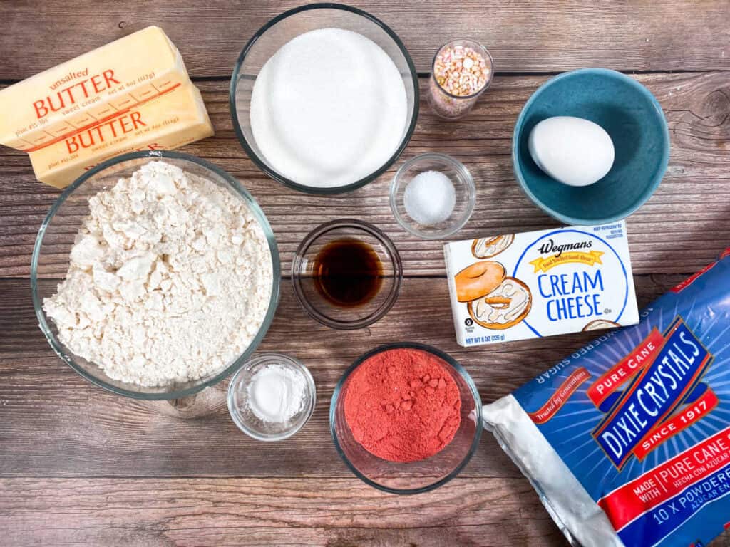 ingredients for strawberries and cream cookie bars - butter, flour, sugar, egg, vanilla, baking powder, cream cheese, freeze dried strawberry powder, powdered sugar, and sprinkles. 