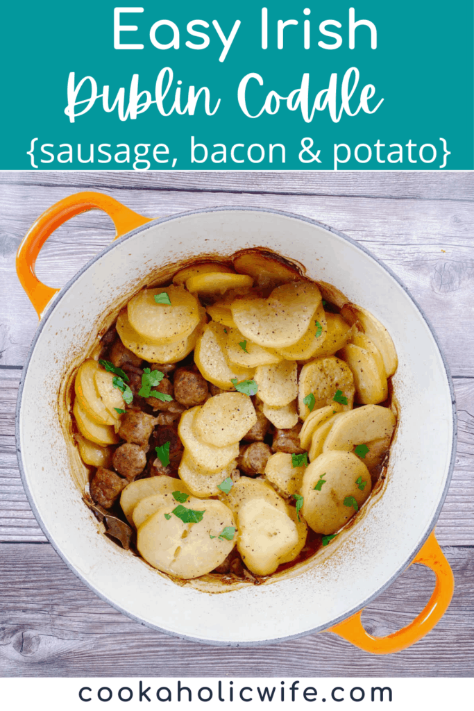 an orange dutch oven sits on a wooden background. The pot is full of pieces of sausage and bacon and sliced potatoes, garnished with parsley, making up this easy irish dublin coddle. 