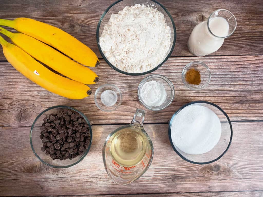 ingredients for jumbo banana chocolate  muffins: bananas, all purpose flour, milk, cinnamon, baking soda, salt, sugar, chocolate chips, vegetable oil. Not pictured: vanilla 