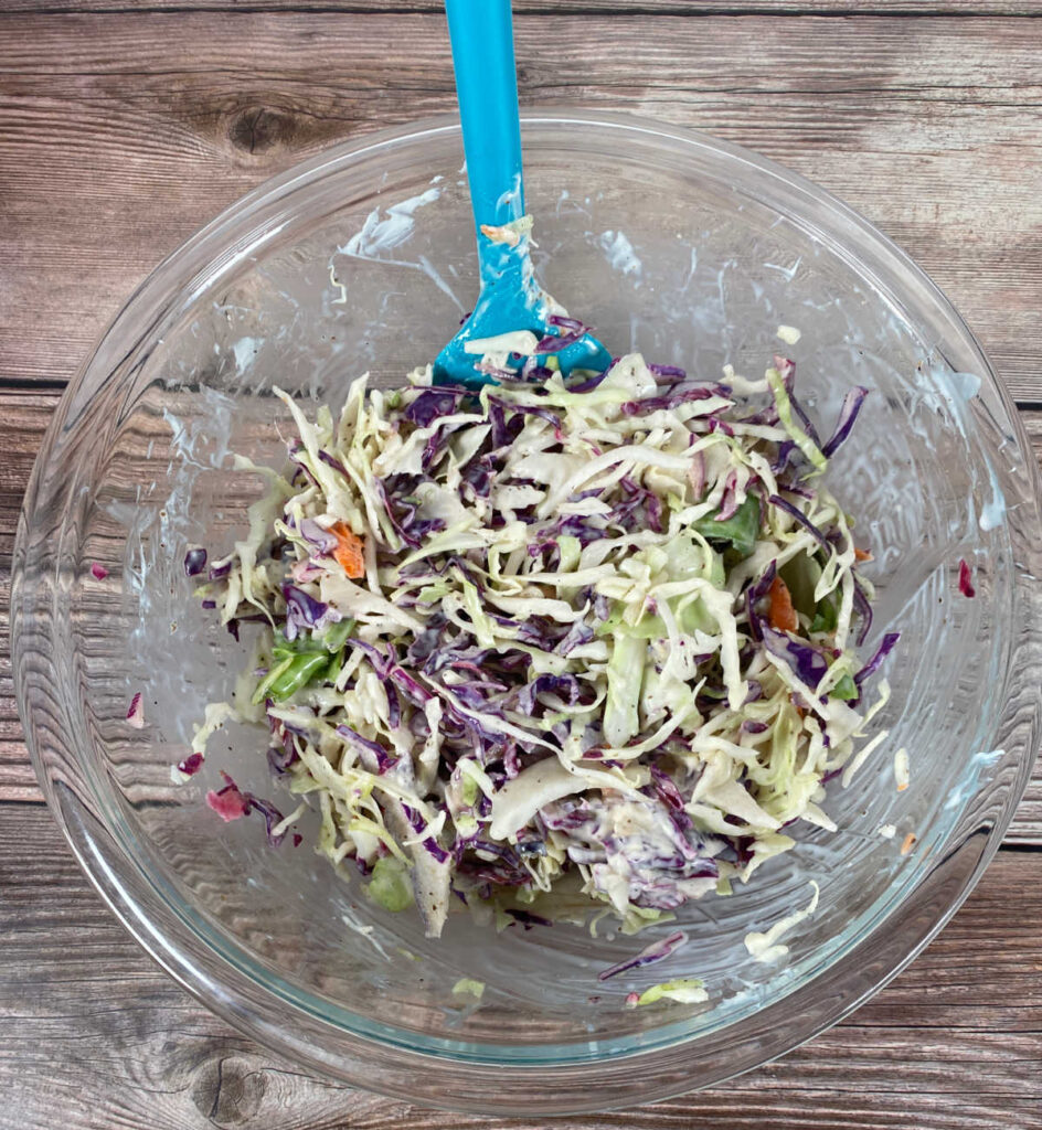 A glass bowl of all the ingredients being mixed together sits on a wooden background. 