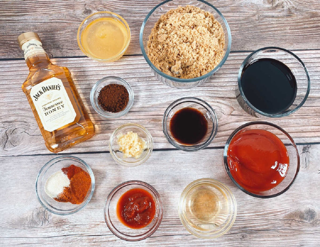 ingredients to make the bbq sauce sit in glass dishes on a wooden background