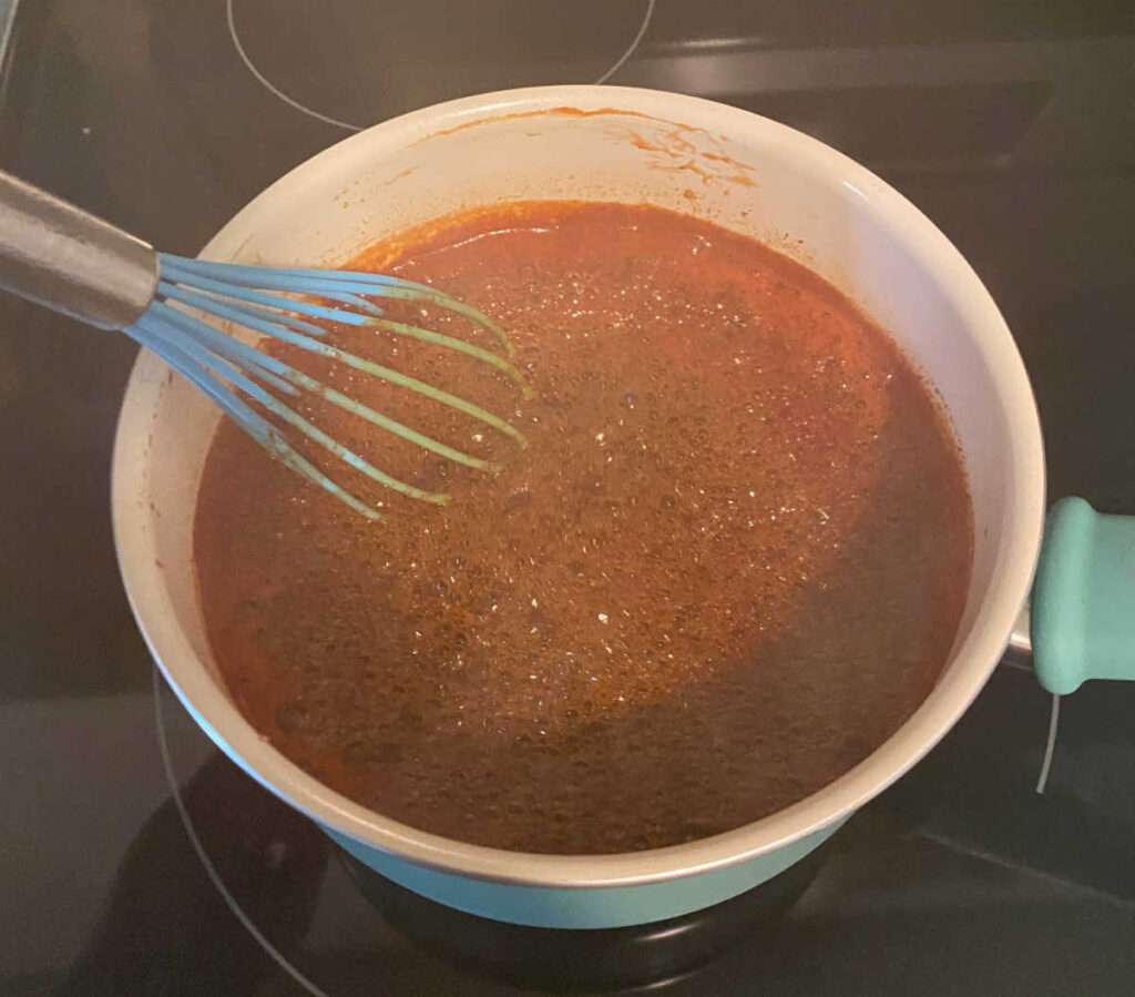 honey whiskey bbq sauce in a turquoise pot boils on the stove 
