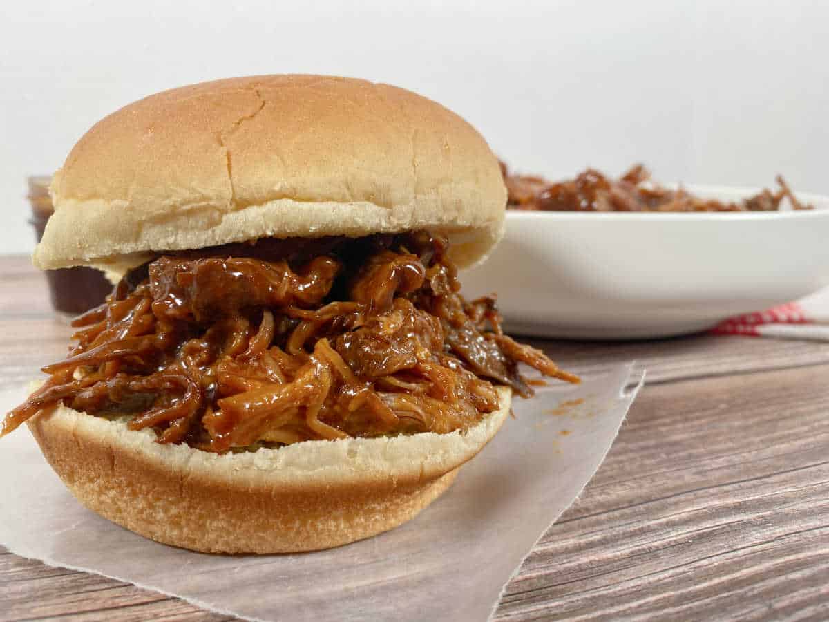 pulled pork sandwich sits on a wooden background