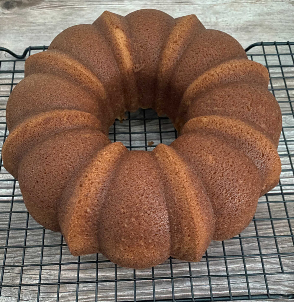 hot milk cake sits on a wire rack, cooling. 