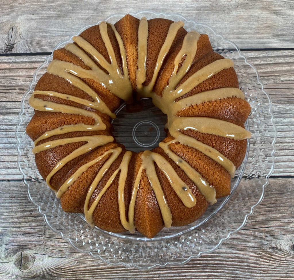 overhead view of the cake, frosted with caramel drizzle, sitting on a glass plate.