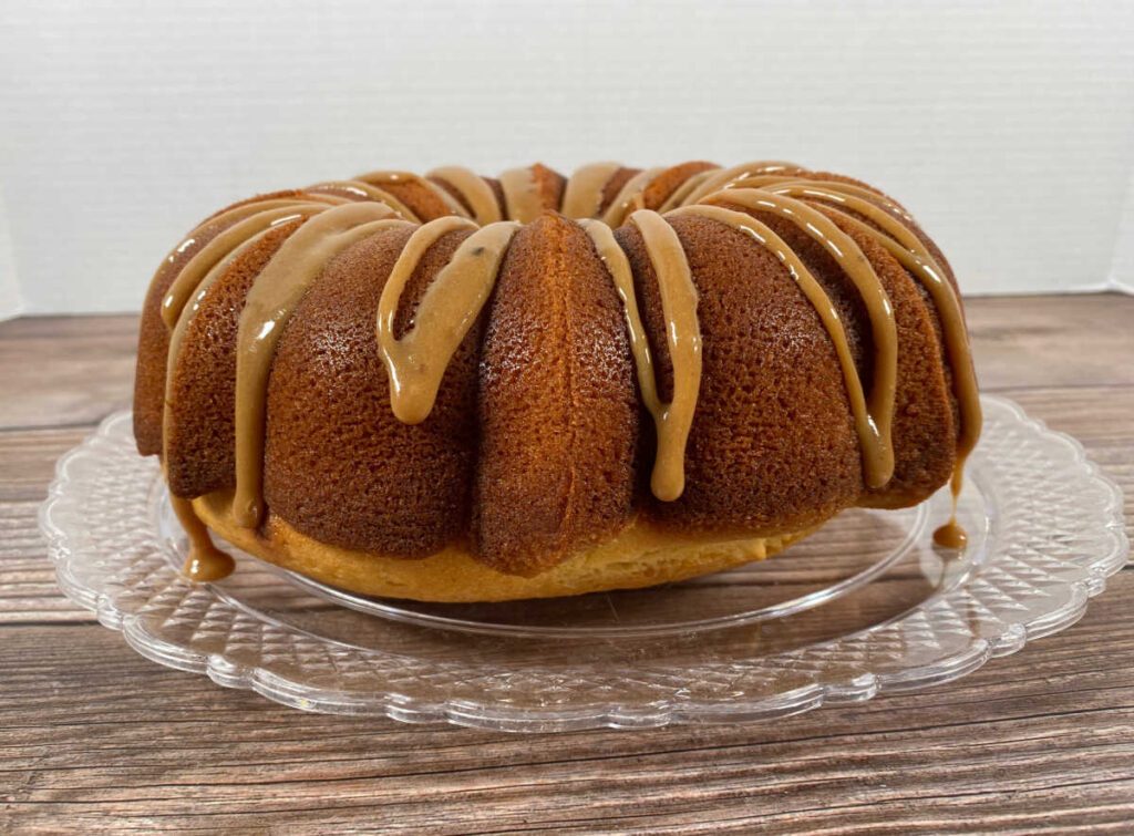 Side view of the cake sitting on a glass plate as the caramel frosting slides down the side 