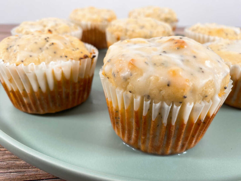 glazed lemon poppy seed muffins sit on a light green plate.