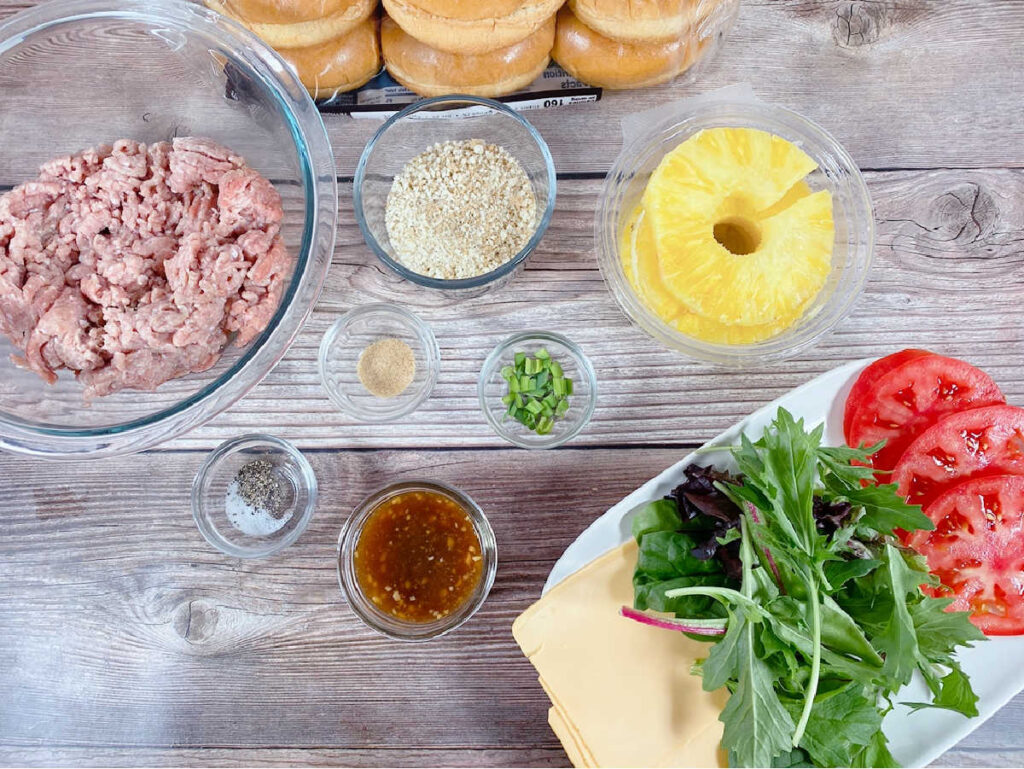 Ingredients for pineapple teriyaki burgers sit on a wooden background. 