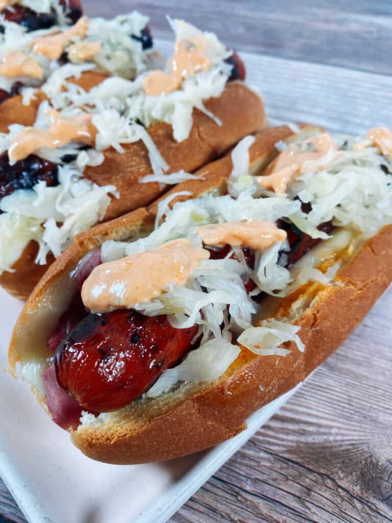 close up of hot dogs with thousand island dressing dripping into the bun. 