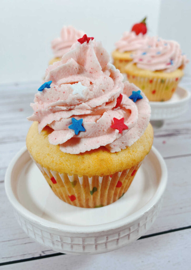 close up of a decorated cupcake, this one is decorated with red, white and blue sprinkled shaped like stars. 