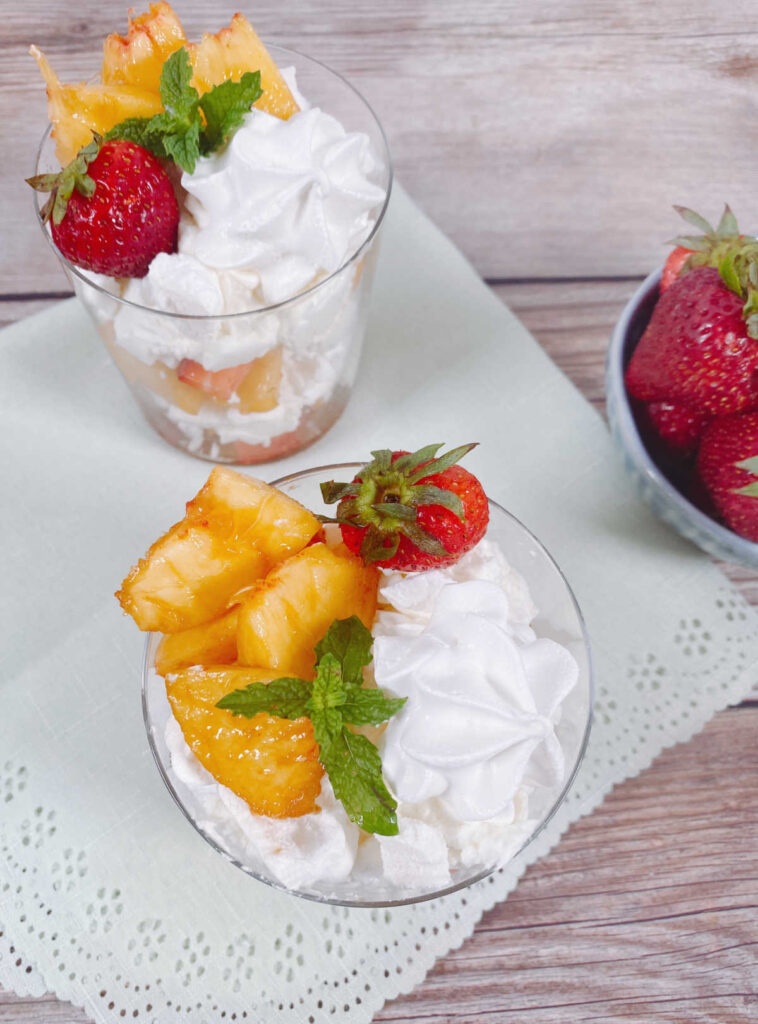 top view image of the glasses sitting on a scalloped napkin with a bowl of strawberries off to the side. 