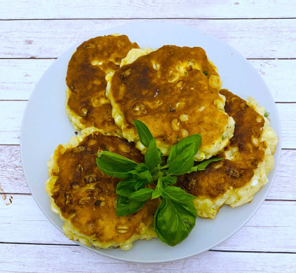 overhead image of the fritters on a white plate, garnished with basil. 