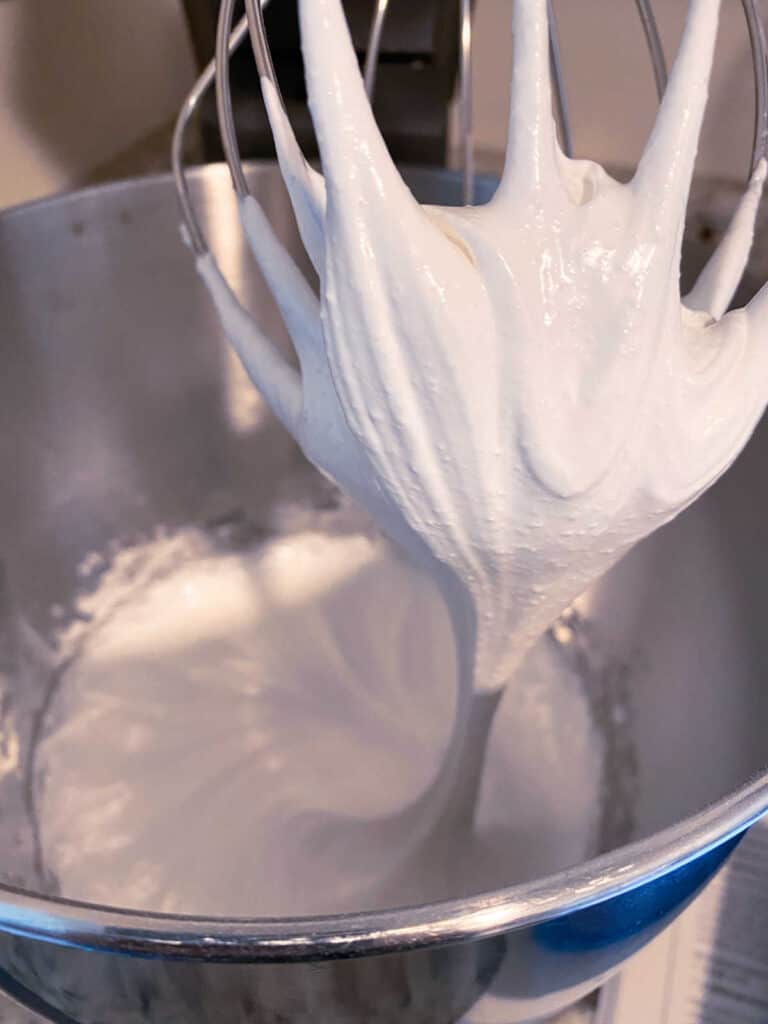 close up image of meringue batter showing stiff peaks in a mixing bowl,