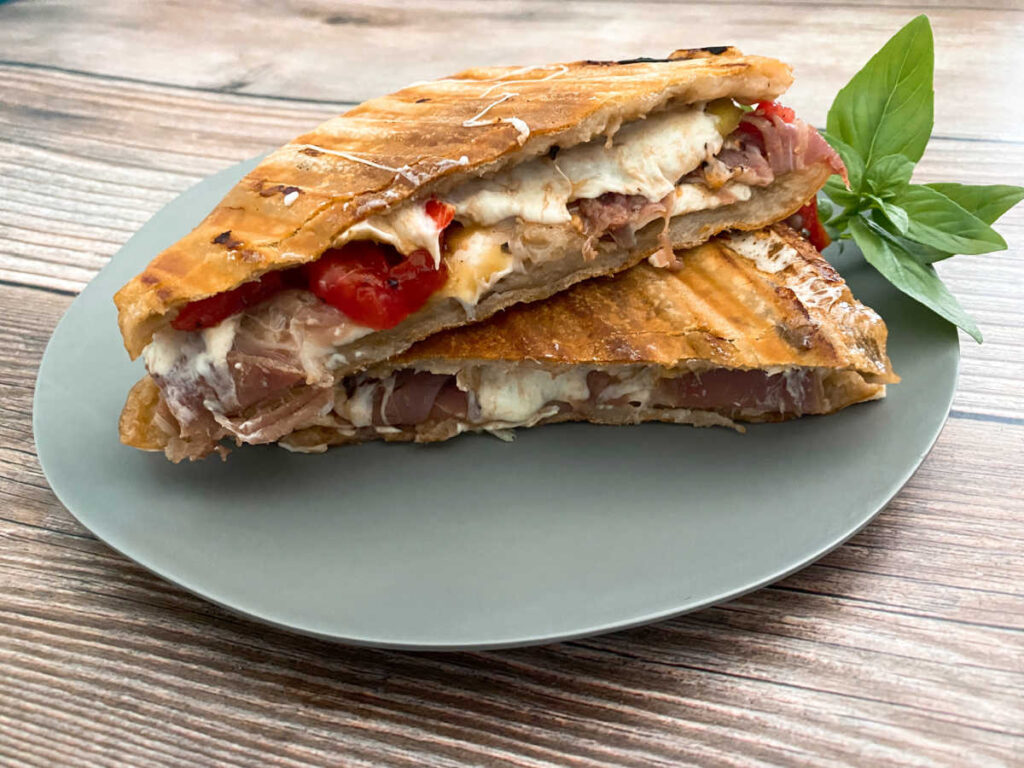 Panini is sliced in half and stacked on top of each other to show the filling of the sandwich. 