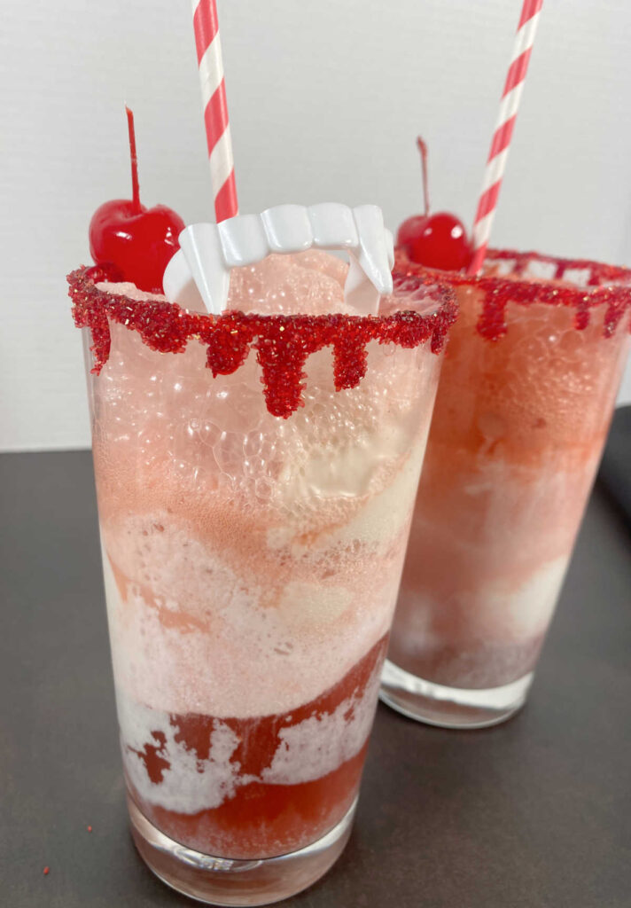 Floats, with ice cream and soda swirled and topped with fake vampire teeth hanging over the edge of the glass, red striped straw and maraschino cherry.