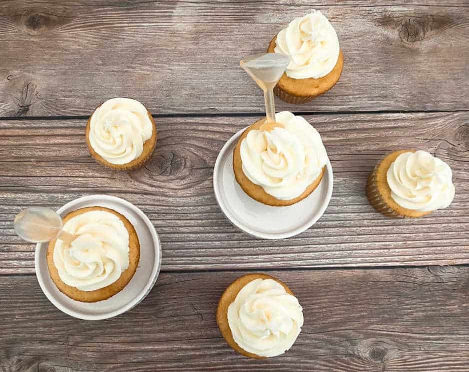 overhead image of cupcakes on white cupcake stands and a wooden background. 