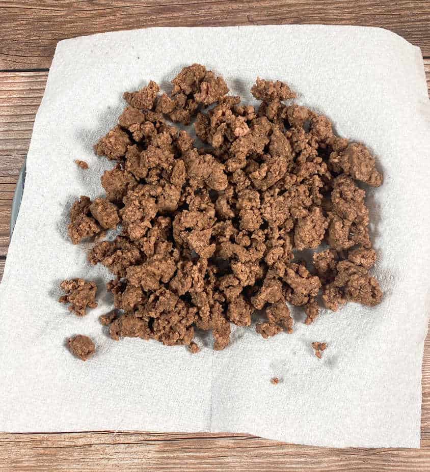 process shot - browned ground beef sits on a paper towel lined plate 