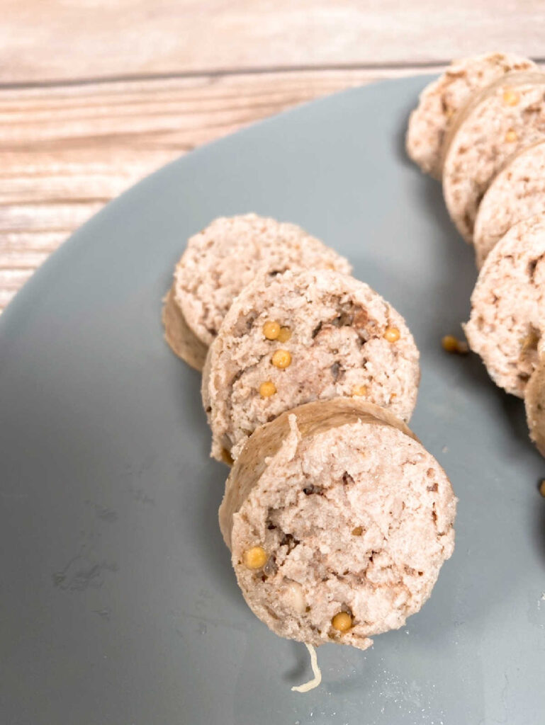 rounds of homemade kielbasa sit on a gray plate.