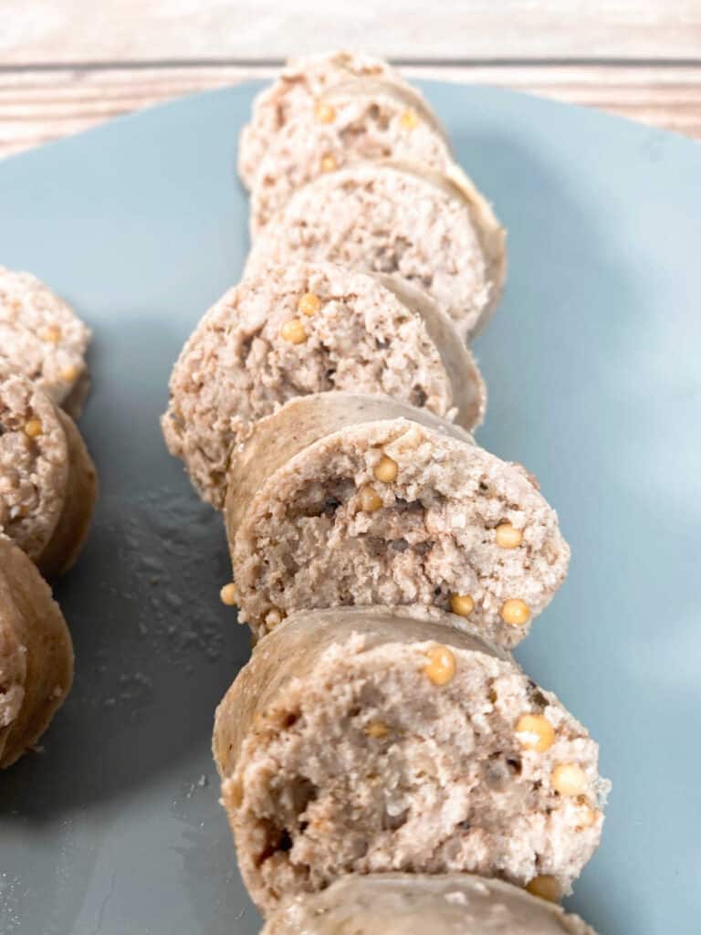 close up image of cooked kielbasa on a gray plate, sliced into rounds 