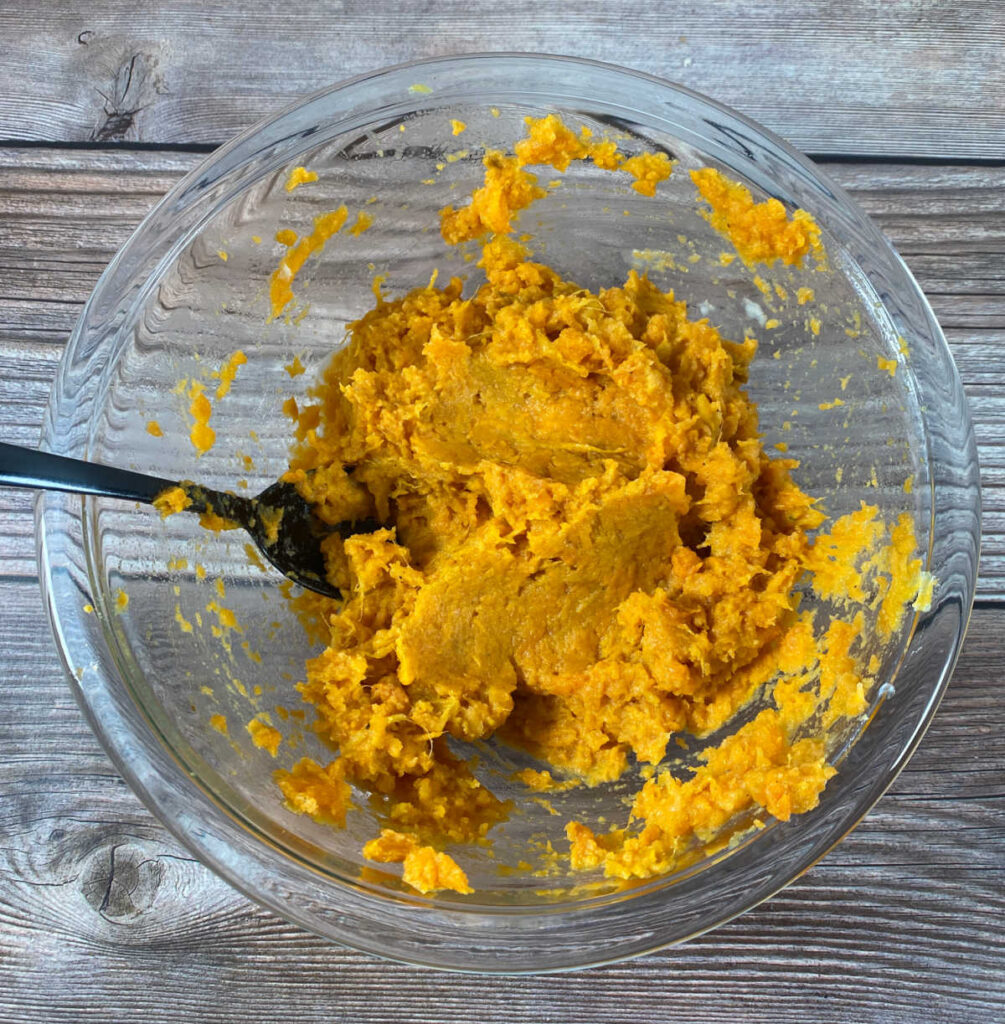 process photo - sweet potatoes mashed with milk, butter and salt in a glass bowl. 