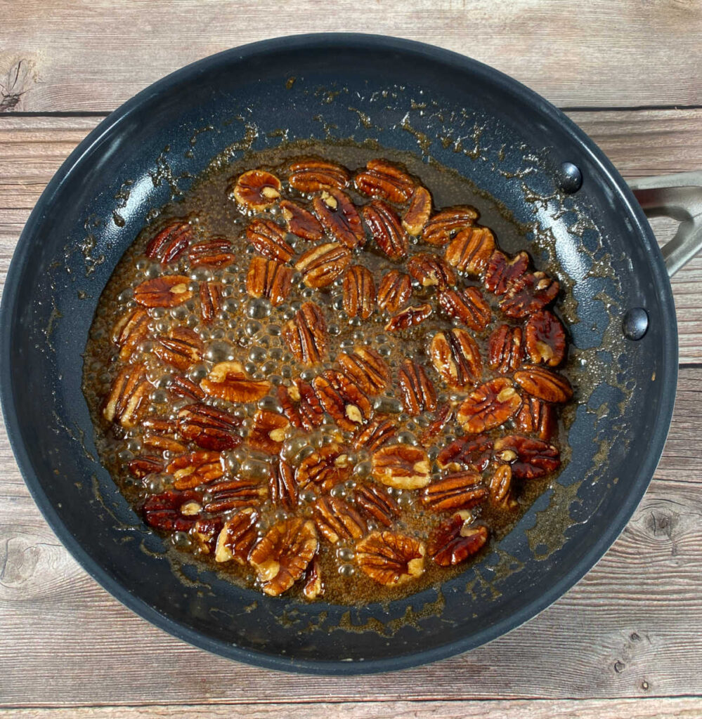 process photo - skillet full of pecans cooking in butter, brown sugar, bourbon and seasonings. 