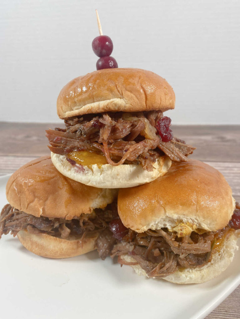 stack of sliders sit on a white plate. 