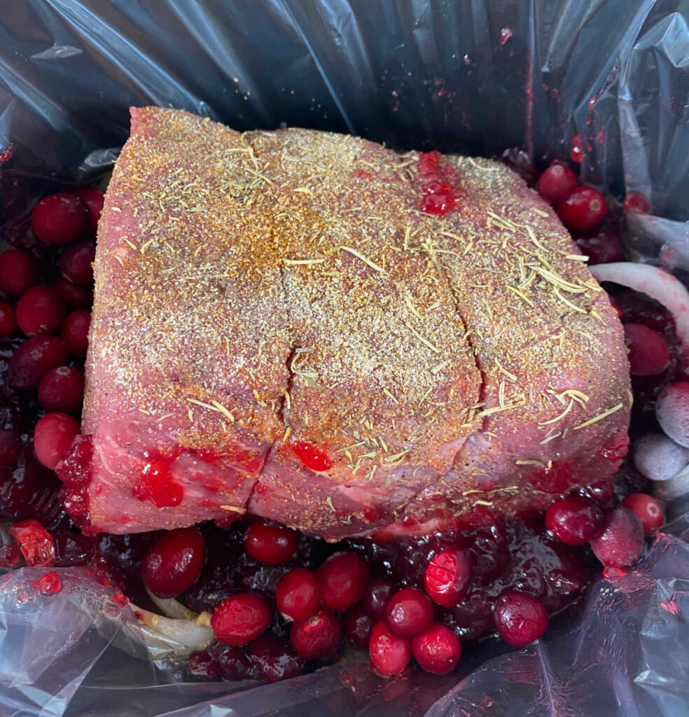 process shot - cranberries and cranberry sauce are added to the slow cooker. 