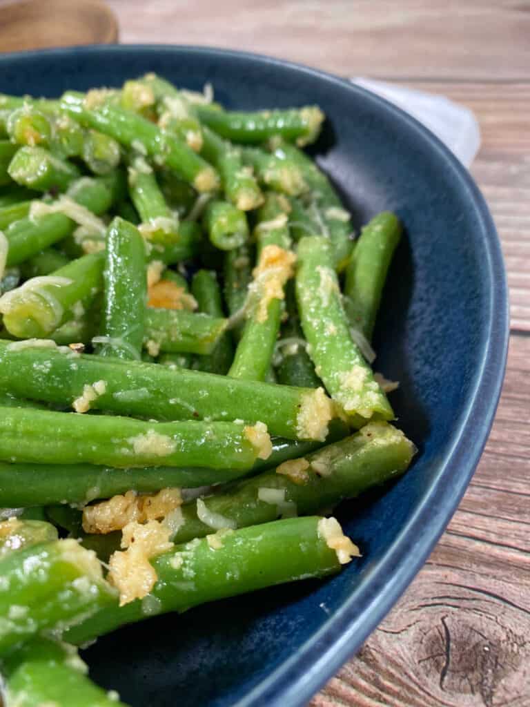 close up image of green beans in a dark blue bowl 