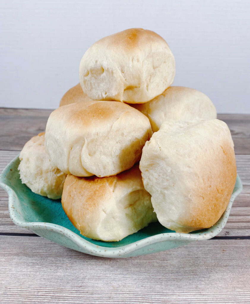 tall stack of dinner rolls sits on a turquoise plate